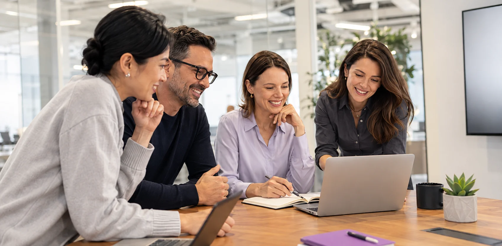 Four Anaptyss colleagues talking around a laptop in the office